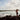 A surfer stands on rocks gazing at the surfing action in Byron Bay, Australia.