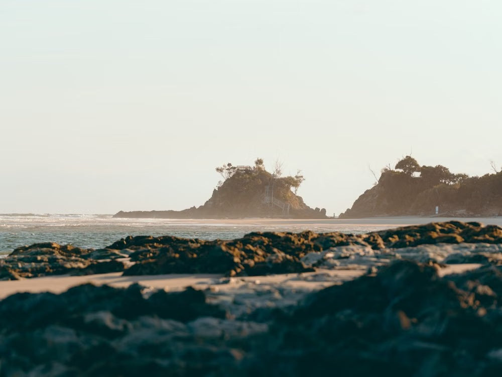 Serene coastal headland with warm sunlight and calm waves for a Luxury Guide to Byron Bay.